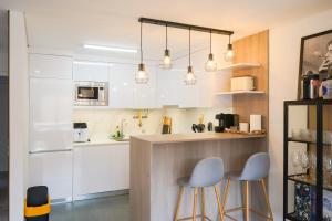 a kitchen with white cabinets and blue stools at Ofir Nature Stay in Fão
