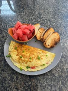 a plate of food with a omelet and a bowl of fruit at La Palma Hostel & Bar in Maragogi