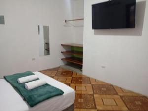a bedroom with a bed with two towels and a flat screen tv at Refugio de Daye in Puerto Ayora
