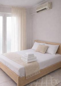 a bedroom with a bed with white sheets and a window at Epanomi Family Apartments in Epanomi +3 photos