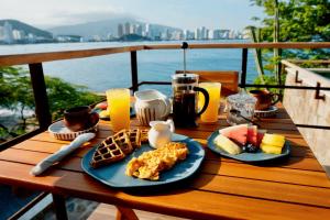 a wooden table with breakfast foods and drinks on it at Perla Roca Hotel Boutique - Beach Front in Santa Marta