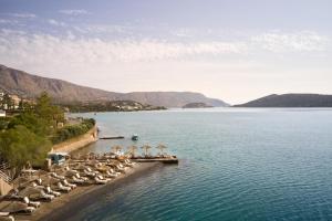 a group of umbrellas and chairs on a beach at Domes Aulus Elounda, Adults only, Curio Collection by Hilton in Elounda