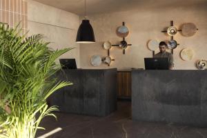 a man standing behind a counter with a laptop at Domes Aulus Elounda, Adults only, Curio Collection by Hilton in Elounda +263 photos