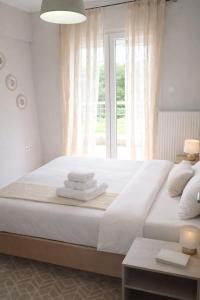 a bedroom with a large white bed with a window at Epanomi Family Apartments in Epanomi