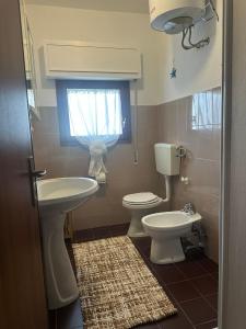 a bathroom with a sink and a toilet and a window at La Terrazza sul Delta in Porto Levante