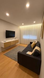a bedroom with a black bed and a flat screen tv at Apartamento de Real in Braga