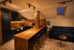 a kitchen with a bar with stools and a couch at Danin's Home in Tuzla