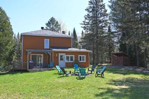 a house with chairs in the yard in front of it at SPA private pond and beach volleyball in Lac-Superieur +33 photos