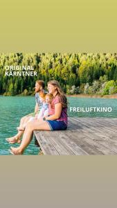 a group of people sitting on a dock on the water at Der Kaerntnerhof am Weissensee, SeeHotel & SeeApartments direkt am See in Weissensee
