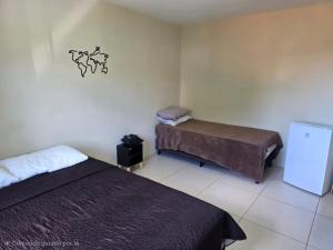 a small room with two beds and a refrigerator at Pousada Sol Radiante in São Pedro da Aldeia