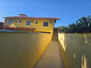 a house with a yellow wall next to a sidewalk at Pousada Sol Radiante in São Pedro da Aldeia