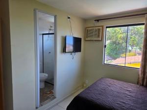 a bedroom with a mirror and a toilet and a television at Pousada Sol Radiante in São Pedro da Aldeia