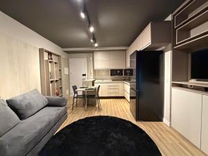 a living room with a gray couch and a kitchen at Studio aconchegante in Belo Horizonte