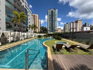 a swimming pool with chairs and a building at Studio aconchegante in Belo Horizonte