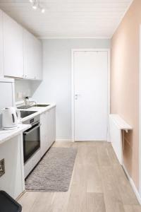 an empty kitchen with white cabinets and a door at Nordic Studio - Gravdal, Lofoten in Haug