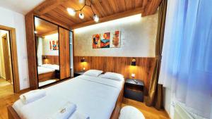a bedroom with a large bed and a mirror at Royal Gardens Centar apartmani in Zlatibor