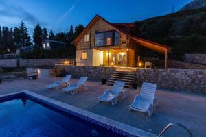 a house with a swimming pool with chairs and a house at Olive Panorama Villa in Dobra Voda