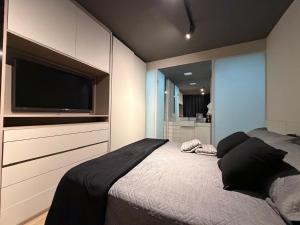a bedroom with a bed with a flat screen tv at Studio aconchegante in Belo Horizonte
