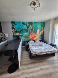 a bedroom with a bed and a desk with a mural at Studio à 2 pas de Disneyland in Esbly