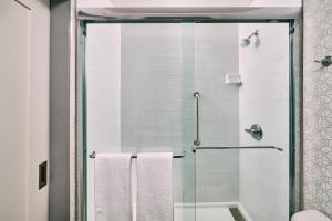 a bathroom with a shower with two white towels at Hampton Inn Anchorage in Anchorage +8 photos