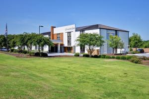 a large building with a green field in front of it at Hampton Inn Auburn in Auburn