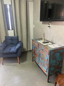 a living room with a blue chair and a dresser at Residencial Mandi in Guaíra