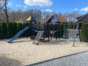 a playground with a slide in the sand at Holiday homes with fireplaces, playground in Lubrza