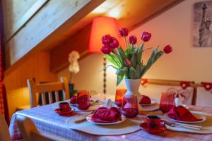 a table with red flowers in a vase on it at Chalet Adda - Appartamento mansarda con garage privato in Bormio