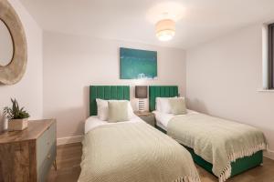 two beds in a room with white walls at Luxury Sea View Apartments in Bude with Garden, Sleep 6 in Bude