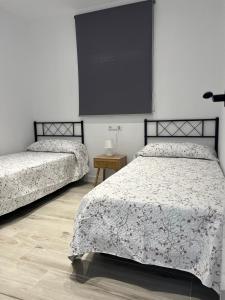 two beds in a room with a black frame at El Rinconcito de la Jara con Parking para varios coches in Sanlúcar de Barrameda