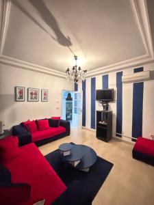 a living room with red couches and a tv at Maison du prince in Yasmine