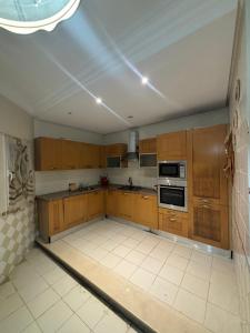 an empty kitchen with wooden cabinets and appliances at Maison du prince in Yasmine