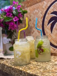 three mason jars with drinks on a table with flowers at Suite Lilo e Stitch - Pousada Castelo do Luar in Penha