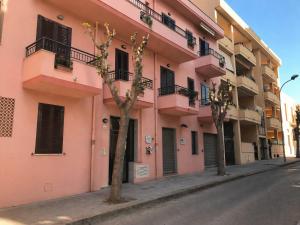 a pink building on a street with trees in front at Casa Rosada Alghero in Alghero