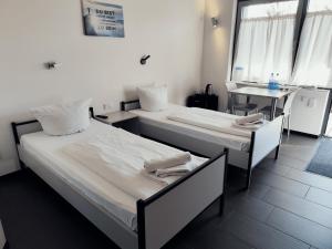 two beds in a room with a table and window at Arena Hotel Waldshut in Waldshut-Tiengen