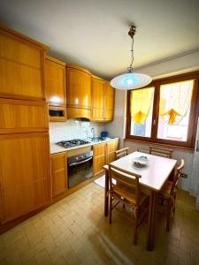 a kitchen with wooden cabinets and a table with chairs at Casa Aurea Lake Como Apartment in Esino Lario