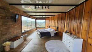 a bedroom with a bed in a room with wooden walls at Cabana do Retiro Refúgio Rústico na Natureza! in Alto da Conceição