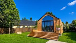a small wooden house with glass windows on a lawn at Cottage de luxe en bois in Longnes