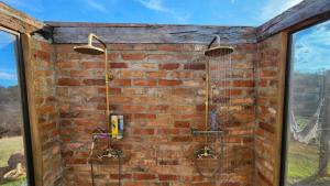 a bathroom with a brick wall with two showers at Cabana do Retiro Refúgio Rústico na Natureza! in Alto da Conceição +41 photos