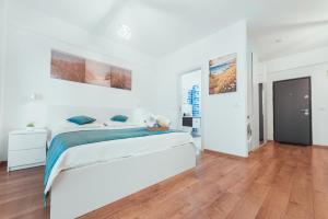 a white bedroom with a bed and a wooden floor at TiLiA Breeze Studio Saturn in Saturn