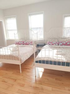 two beds in a room with two windows at Sunny Ensuite Room with 2 Queen Beds-2A in Halifax
