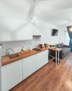 a kitchen with white cabinets and a table and a couch at TiLiA Breeze Studio Saturn in Saturn