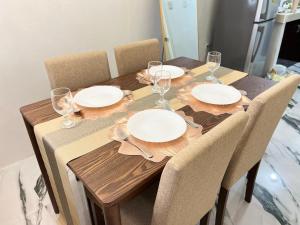 a wooden table with plates and wine glasses on it at Solara Villa, Gensan in General Santos