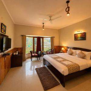 a bedroom with a large bed and a flat screen tv at The Regal IVY Hotel in Nainital