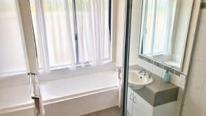a bathroom with a tub and a sink and a window at Wagon Holiday Home in Broadwater