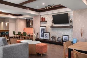 a living room with a tv on a brick wall at Hampton Inn & Suites Fresno in Fresno