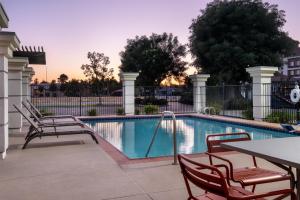 a swimming pool with two chairs and a table and a table and chairs at Hampton Inn & Suites Fresno in Fresno