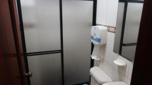 a bathroom with a toilet and a glass door at Centro Macas in Macas +68 photos