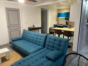a blue couch in a living room with a kitchen at Ti kaz belair in Le Diamant
