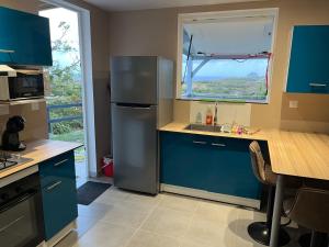 a kitchen with blue cabinets and a stainless steel refrigerator at Ti kaz belair in Le Diamant +3 photos